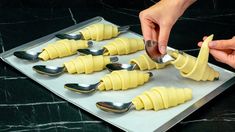 a person scooping cheese from a tray with spoons on it to make ravioli