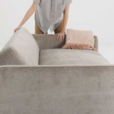 a woman standing on top of a couch with her hands on the back of it