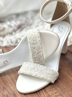 a pair of white high heeled shoes sitting on top of a wooden floor