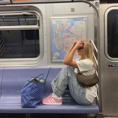 a woman sitting on a subway train with her hand in her hair, looking out the window