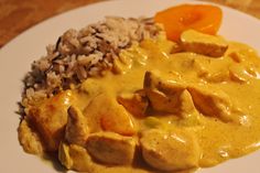 a white plate topped with meat and rice covered in gravy on top of a wooden table