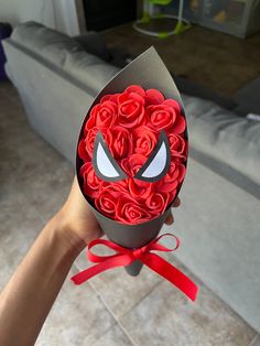 someone is holding up a box with roses in the shape of a spiderman face