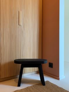 a wooden bench sitting in front of a wall with vertical blinds on it's side