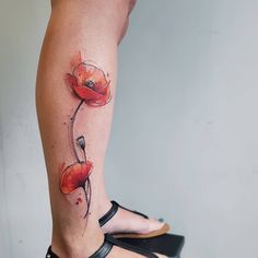 a woman's leg with a red flower tattoo on it