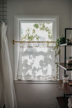 a bathroom with a window, shelf and shower curtain