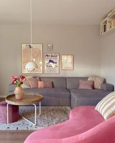 a living room with pink couches and pictures hanging on the wall above it's coffee table