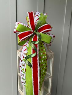 a green and red christmas bow on top of a white doorknob with polka dots