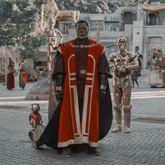 a man dressed in costume standing on a brick street next to two other men wearing costumes