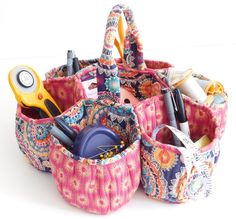 an assortment of crafting supplies in a pink and blue fabric basket on a white surface