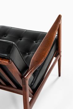 a wooden chair with black leather upholstered seat and backrest, on a white background