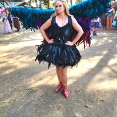 a woman in a black dress with blue and purple feathers on her wings, posing for the camera