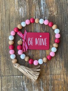 a beaded bracelet with the word be mine on it and a tasseled charm