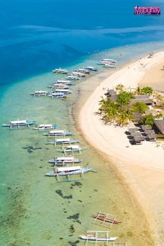 several boats are docked on the shore of a tropical island with white sand and clear blue water