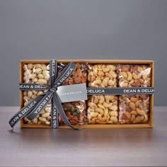 a wooden box filled with assorted nuts and wrapped in black ribbon on top of a table