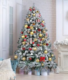 a white christmas tree with red, gold and silver ornaments in front of a fireplace