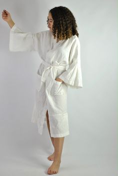 "This is our no. 60 of Conscious Clothing Concept #stayhome This lovely white A-line loose fitting robe is made of pure quality linen. Very modern approach to traditional white spa gown. It has got very flattering wide sleeves that match the bottom of the dress. This unique piece of loungewear can be very versatile. It is great and comfy to wear around the house, hotel or spa. It can be treated as the dress or loose shirt over the shorts for summer look. Perfect for home and the beach. It is the Long White Robe For Home, White Robe With Kimono Sleeves For Home, Summer Belted Kimono For Daywear, Summer Daywear Belted Kimono, Cream Summer Daywear Robe, White Spring Vacation Robe, White Tie Waist Long Sleeve Robe, White Wrap Dress For Daywear, Elegant White Robe For Relaxation