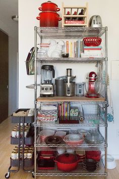 a metal shelf filled with pots and pans on top of wooden floor next to wall