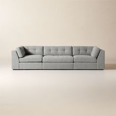 a gray couch sitting on top of a white floor next to a beige wall in an empty room