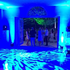 some people are standing around in a room with blue lights on the walls and floor