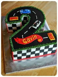 a birthday cake that is shaped like a number two with cars on the road and grass