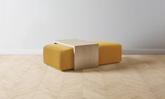 a small yellow bench sitting on top of a hard wood floor next to a white wall