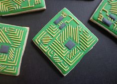 four green and yellow decorated cookies sitting on top of a black table next to each other