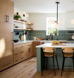 a kitchen with two stools at the center of the island and several lights hanging from the ceiling