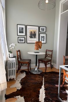 two chairs and a table in a small room with pictures on the wall behind them