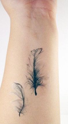 a feather tattoo on the back of a woman's arm