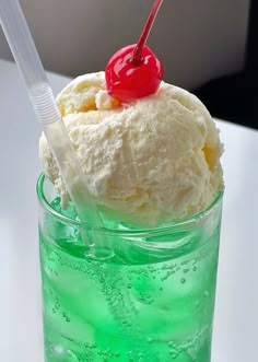 an ice cream sundae with a cherry on top in a tall glass filled with green liquid