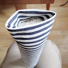 a white and black striped vase sitting on top of a wooden table next to a chair