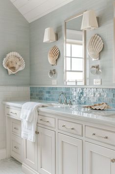 a white bathroom with blue tile and sea shells on the counter top, along with two sinks