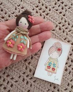 a tiny doll is sitting on someone's hand next to a small card that says i love you