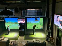 three people playing golf on large screens in a room with couches and chairs around them