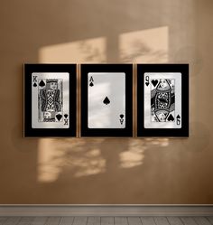 three playing cards hanging on the wall in front of a window with sunlight streaming through them