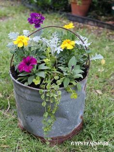 a bucket filled with flowers sitting on top of a lush green field