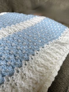 a blue and white crocheted blanket sitting on top of a couch