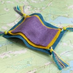 a purple and yellow felt pouch with tassels sitting on top of a map