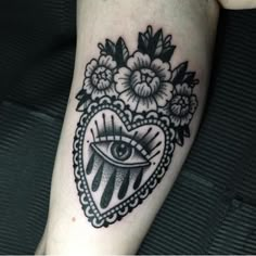 a black and white tattoo with an all seeing eye in the heart surrounded by flowers