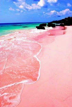 the beach is pink and green with waves coming in