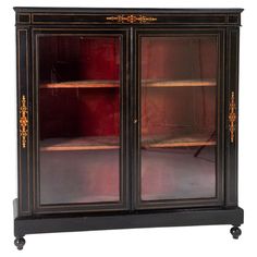 an antique black cabinet with glass doors and gold trimmings on the bottom shelf