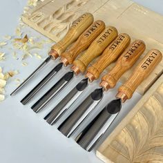 five wooden carving tools are lined up in a row