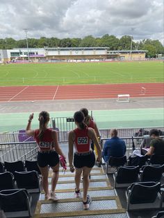 two girls are walking up the stairs in front of an empty stadium