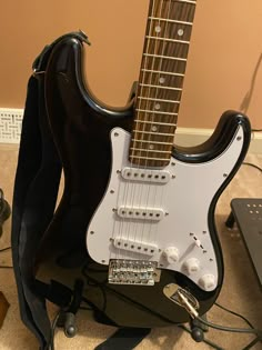 an electric guitar sitting on top of a black stand next to a laptop and headphones