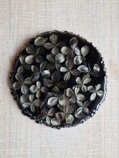 a pie with leaves on it sitting on top of a cloth covered table next to a white wall