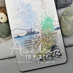 an art journal with watercolors and ink on it, next to some rocks