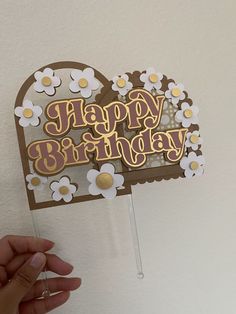 someone holding up a happy birthday card with daisies on the front and back of it