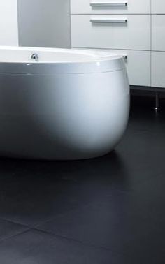 a white bath tub sitting on top of a black floor