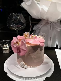 a pink and white cake on a plate with flowers in the middle next to it