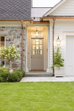 a house with a gray front door and green grass